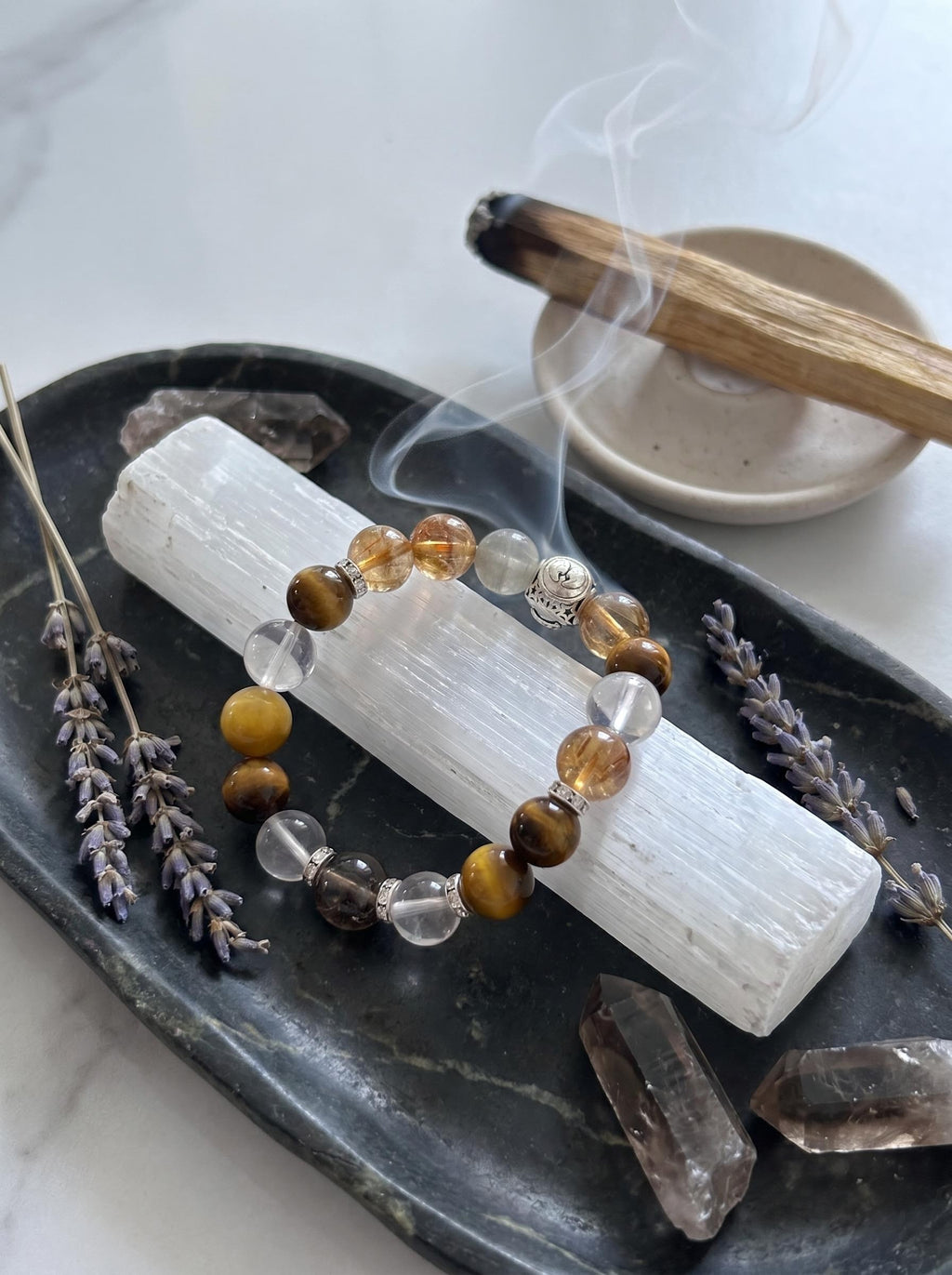 Gemini Frequency crystal bracelet 
on selenite charging plate 
with white sage bundle and moonstone sphere, 
gemini zodiac crystal cleansing ritual cool tones