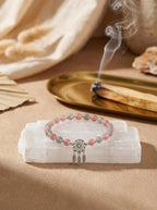Dream Catcher strawberry quartz bracelet
on selenite charging plate with white sage,
empath protection crystal bracelet cleansing ritual