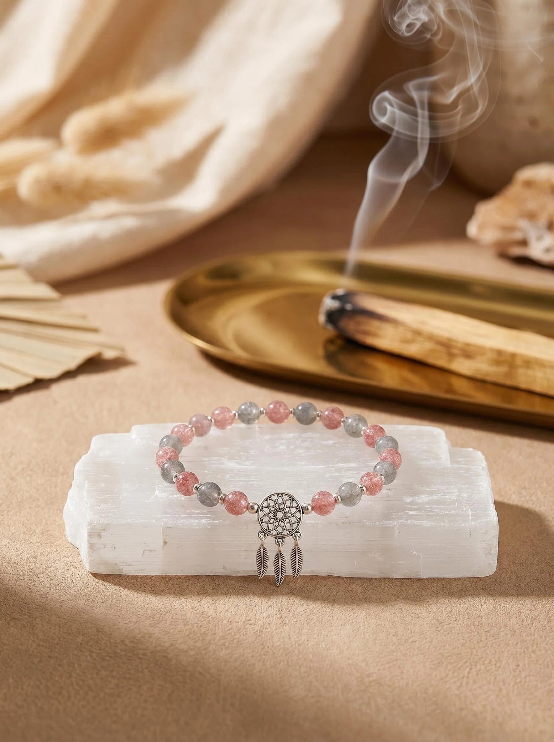 Dream Catcher strawberry quartz bracelet
on selenite charging plate with white sage,
empath protection crystal bracelet cleansing ritual