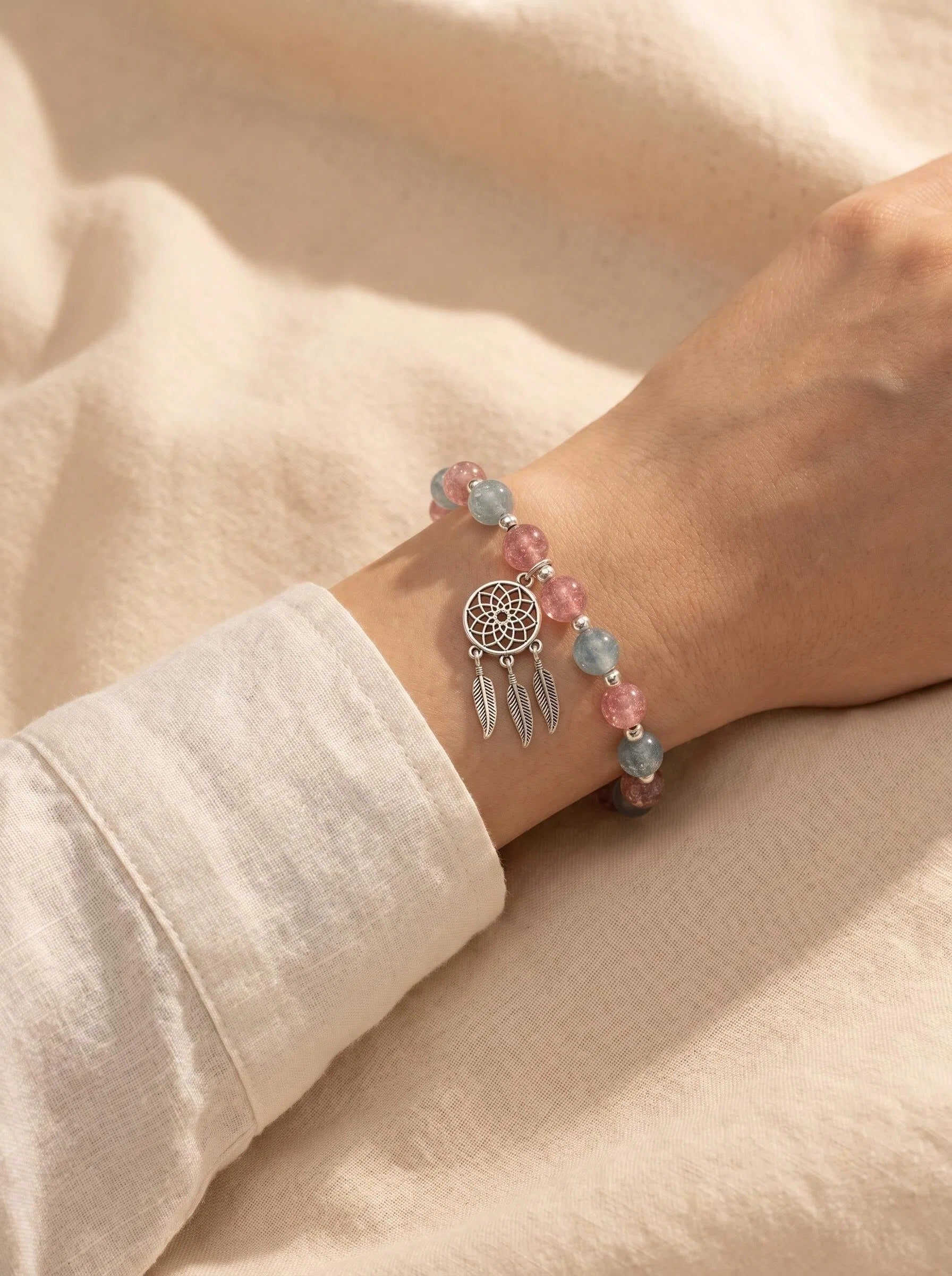 Woman's wrist wearing Dream Catcher crystal bracelet
with red green strawberry quartz and silver charm,
boho spiritual lifestyle photography
heart chakra empath protection jewelry
