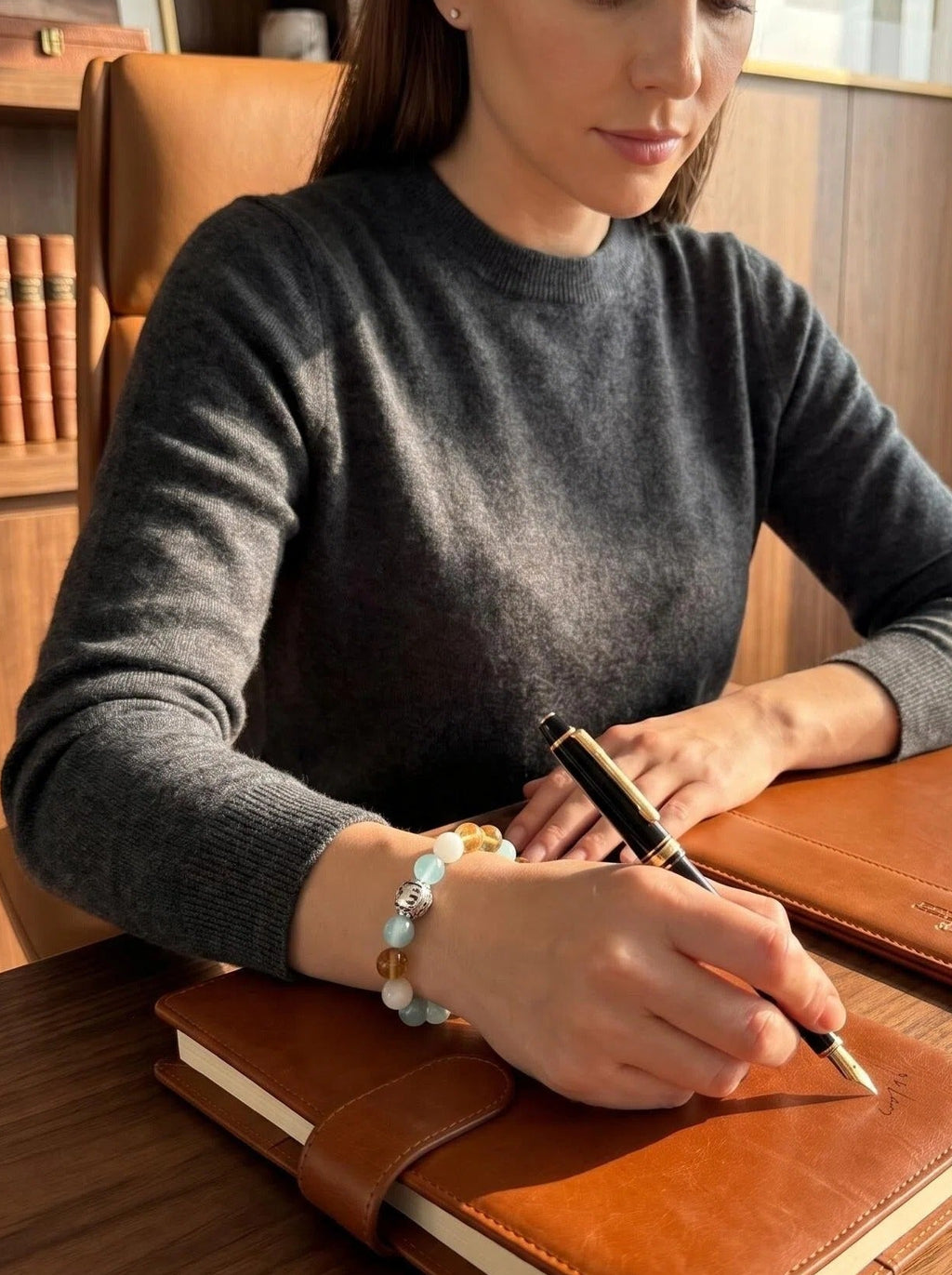Woman's wrist wearing Taurus Throne crystal bracelet 
with gold rutilated quartz and aquamarine beads, 
warm golden light luxury crystal jewelry lifestyle