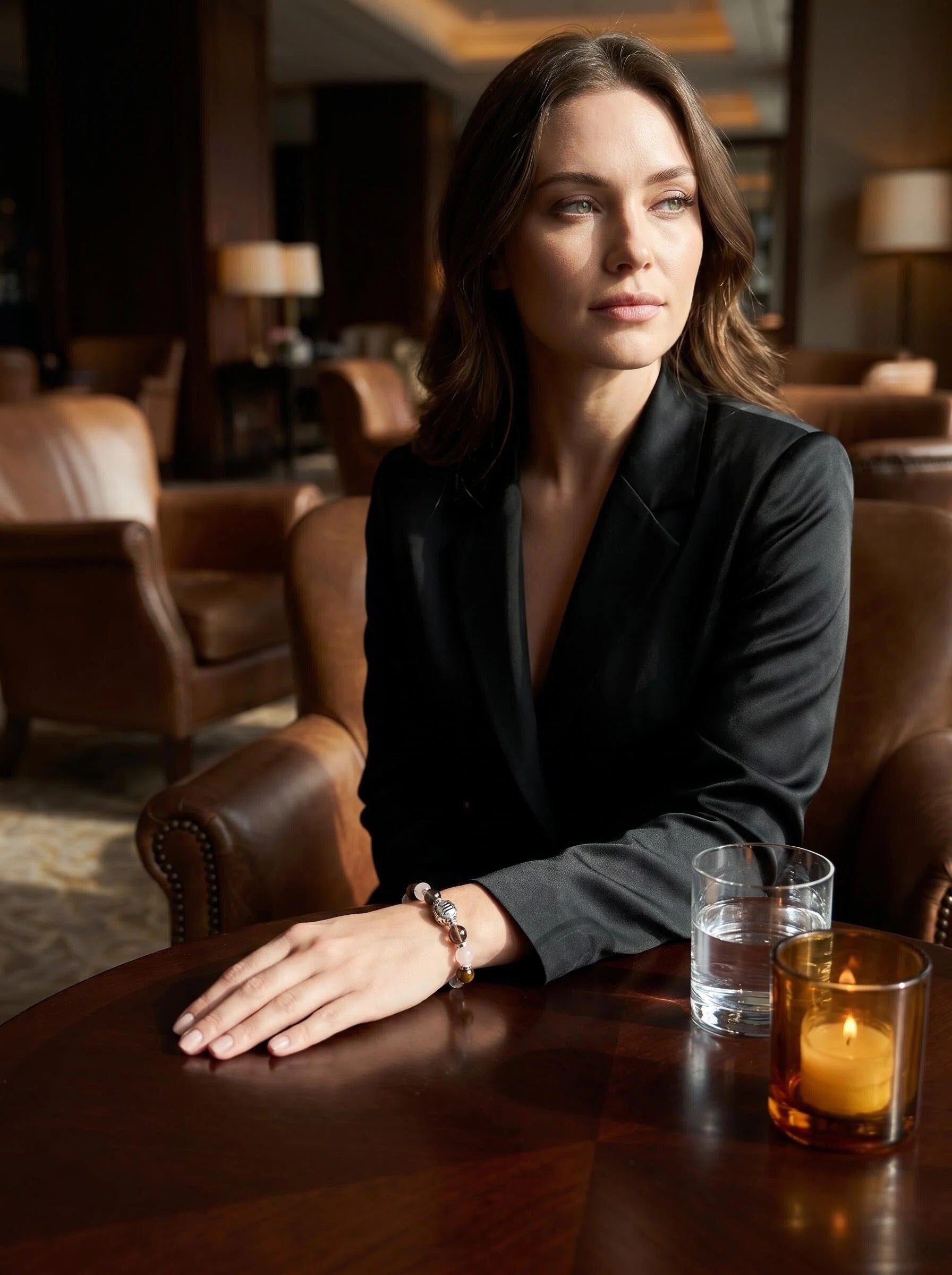 Woman's wrist wearing Scorpio Sovereign crystal bracelet 
with smoky quartz and tiger's eye beads, 
dark moody lifestyle crystal jewelry photography