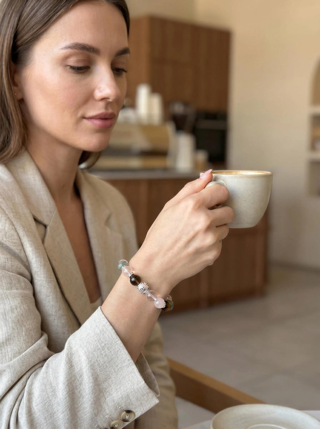 Woman's wrist wearing Libra Luminary crystal bracelet 
with green phantom quartz and rose quartz beads, 
soft warm lifestyle crystal jewelry photography