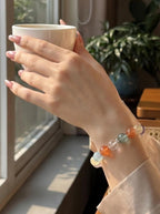 Woman's wrist wearing Full Bloom 7-stone crystal bracelet
with citrine aquamarine and rose quartz beads,
warm radiant lifestyle photography
complete chakra healing jewelry aesthetic
