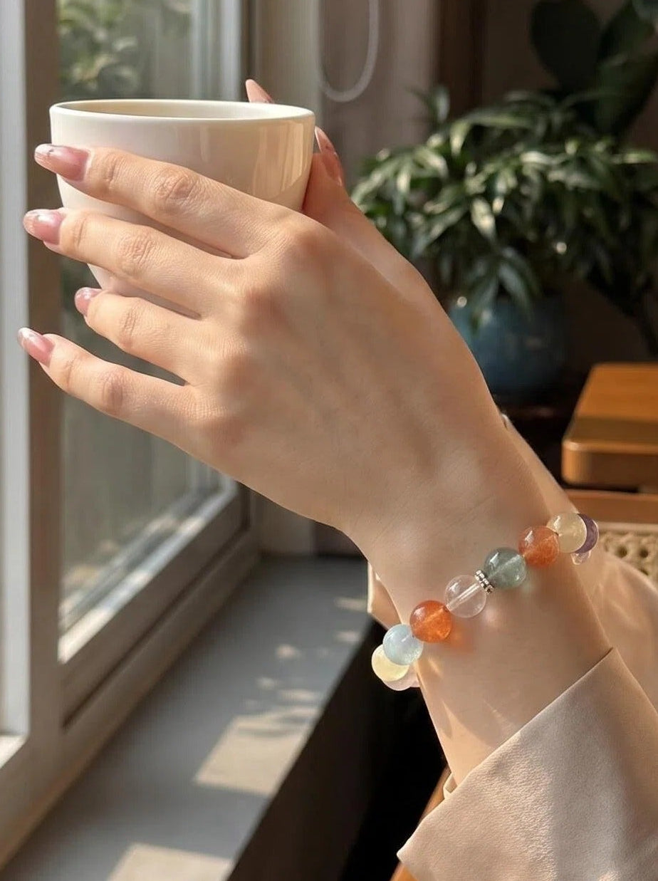 Woman's wrist wearing Full Bloom 7-stone crystal bracelet
with citrine aquamarine and rose quartz beads,
warm radiant lifestyle photography
complete chakra healing jewelry aesthetic