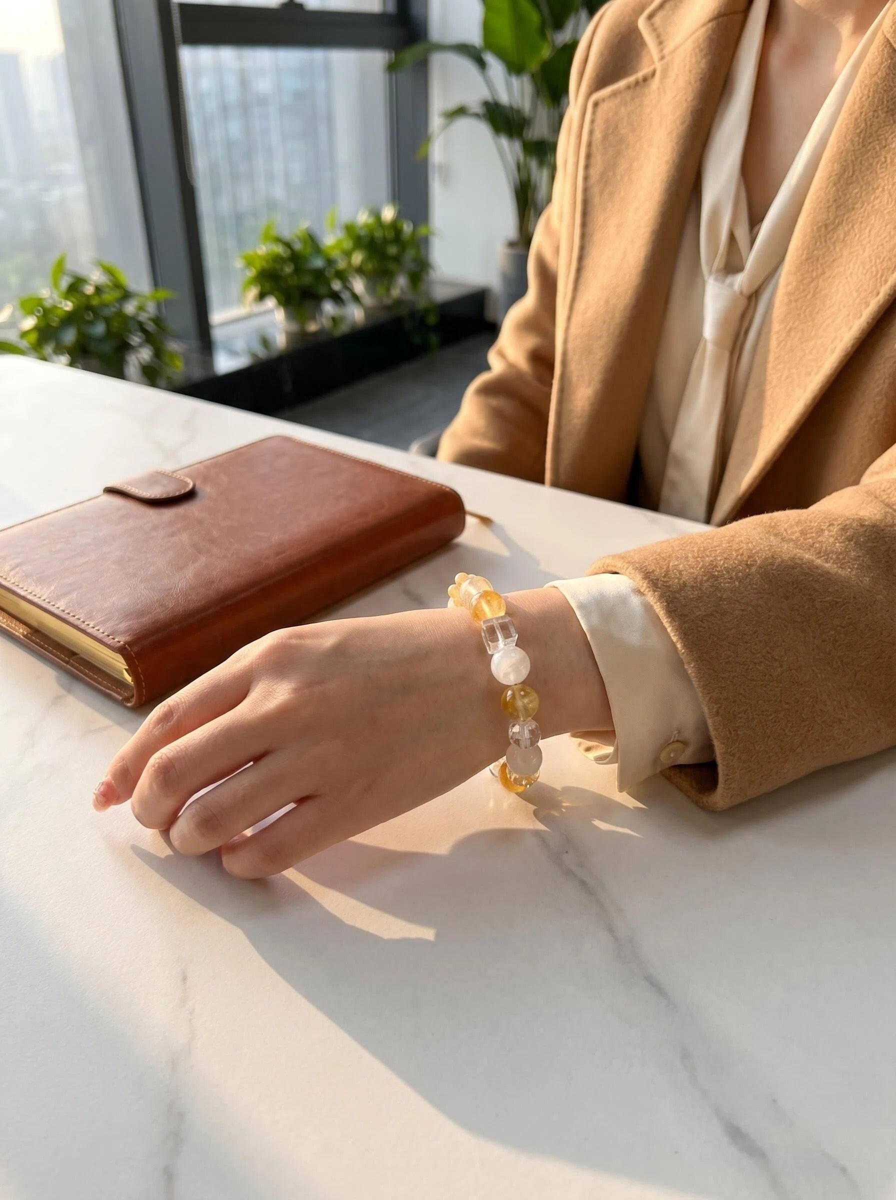 Woman's wrist wearing Golden Drift crystal bracelet
with yellow fluorite and white phantom quartz beads,
warm golden light lifestyle photography
wealth manifestation crystal jewelry