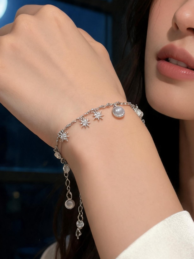 Woman's wrist wearing the blue and grey moonstone crystal bracelet resting on a windowsill at dusk