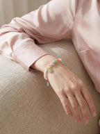 Woman's wrist wearing Pearl & Bloom crystal bracelet
with Swarovski pearl and strawberry quartz beads,
soft elegant lifestyle photography
heart chakra grace crystal jewelry