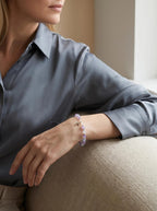 Woman's wrist wearing Sacred Light crystal bracelet
with amethyst and grey moonstone beads and silver cross,
soft calm lifestyle photography
divine protection faith crystal jewelry