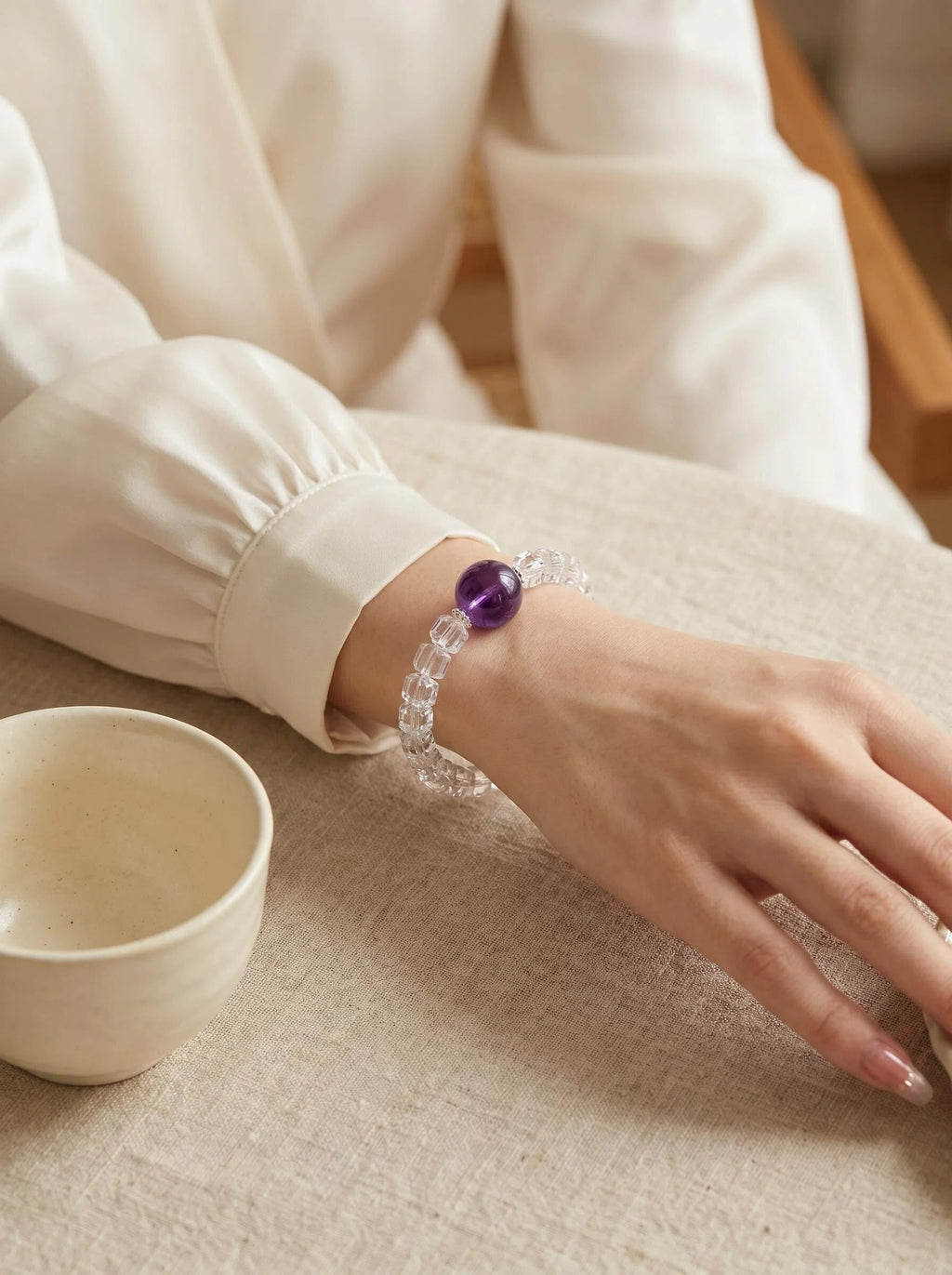 Woman's wrist wearing Still Mind bracelet
with amethyst and clear quartz wheel beads,
soft minimal calm lifestyle photography,
sleep and anxiety relief crystal jewelry