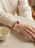 Woman's wrist wearing Still Mind bracelet
with amethyst and clear quartz wheel beads,
soft minimal calm lifestyle photography,
sleep and anxiety relief crystal jewelry