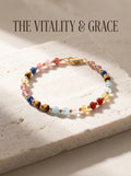 The Vitality Grace crystal bracelet with strawberry quartz 
kyanite yellow tiger's eye aquamarine clear quartz 
yellow topaz and red agate beads, 
7-stone vitality healing bracelet on white marble surface