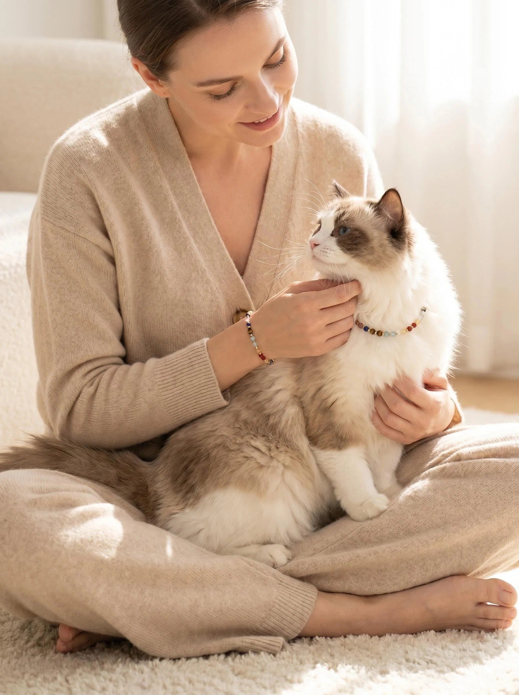 Woman's wrist wearing Vitality Grace bracelet 
with small cat or dog wearing matching crystal collar, 
human and pet matching crystal set lifestyle photography