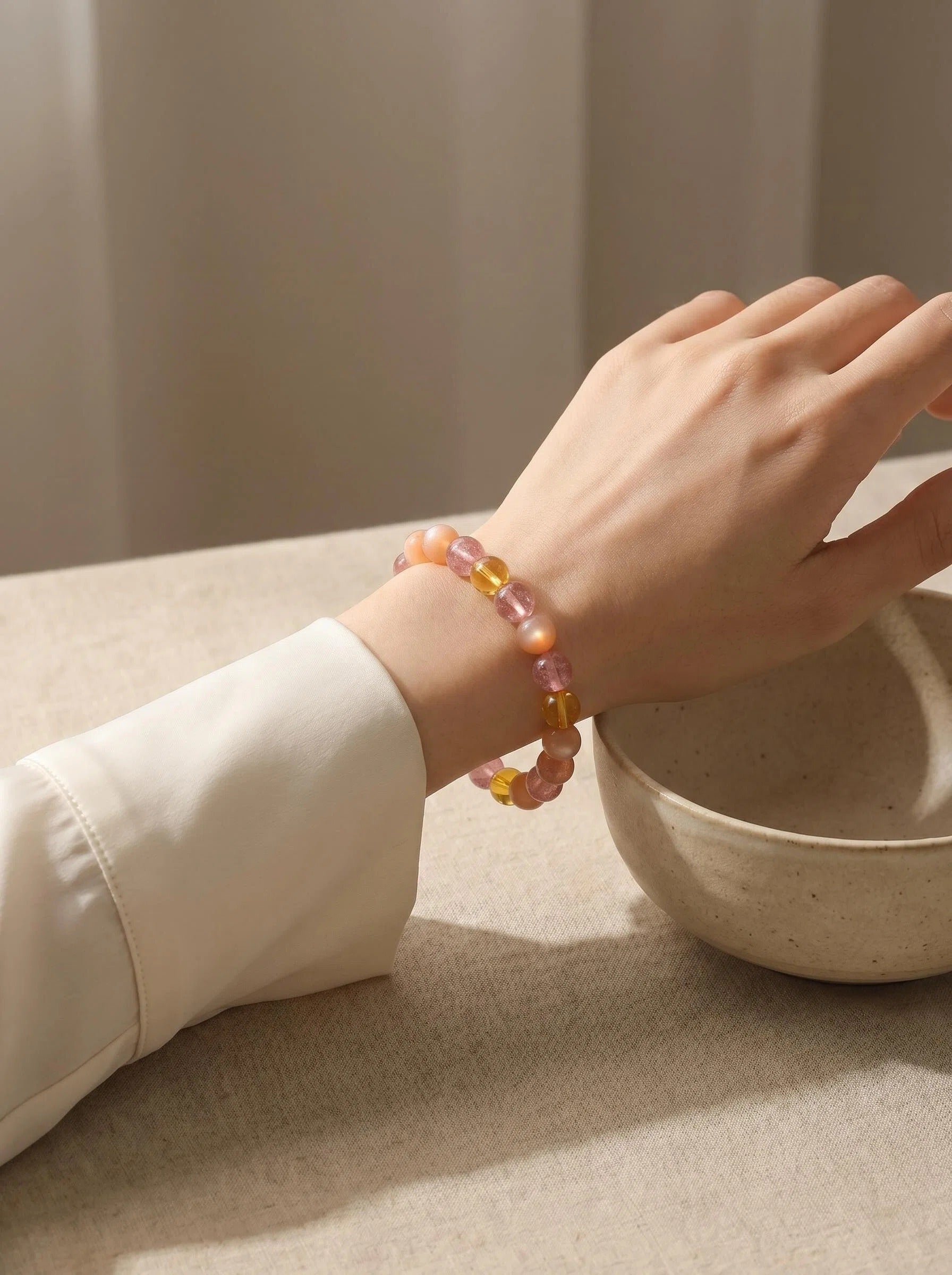 Woman's wrist wearing Warm Light crystal bracelet
with orange moonstone and amber beads,
soft warm golden light lifestyle photography
feminine energy crystal jewelry
